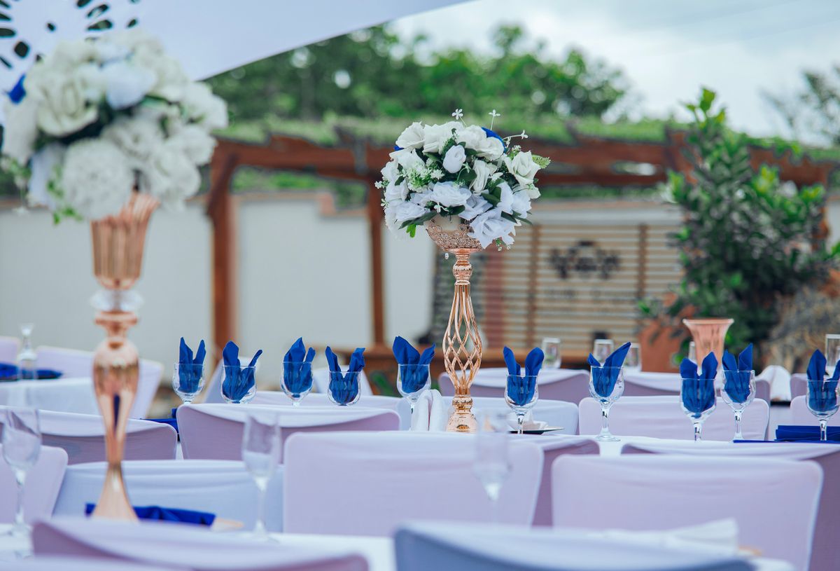 A beautifully decorated outdoor dinner setting with white flowers and blue accents.